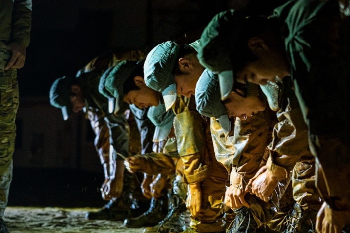 一隊穿著迷彩服的韓國年輕人正在晚上進行軍事訓練，全神貫注地系綁腳繩。