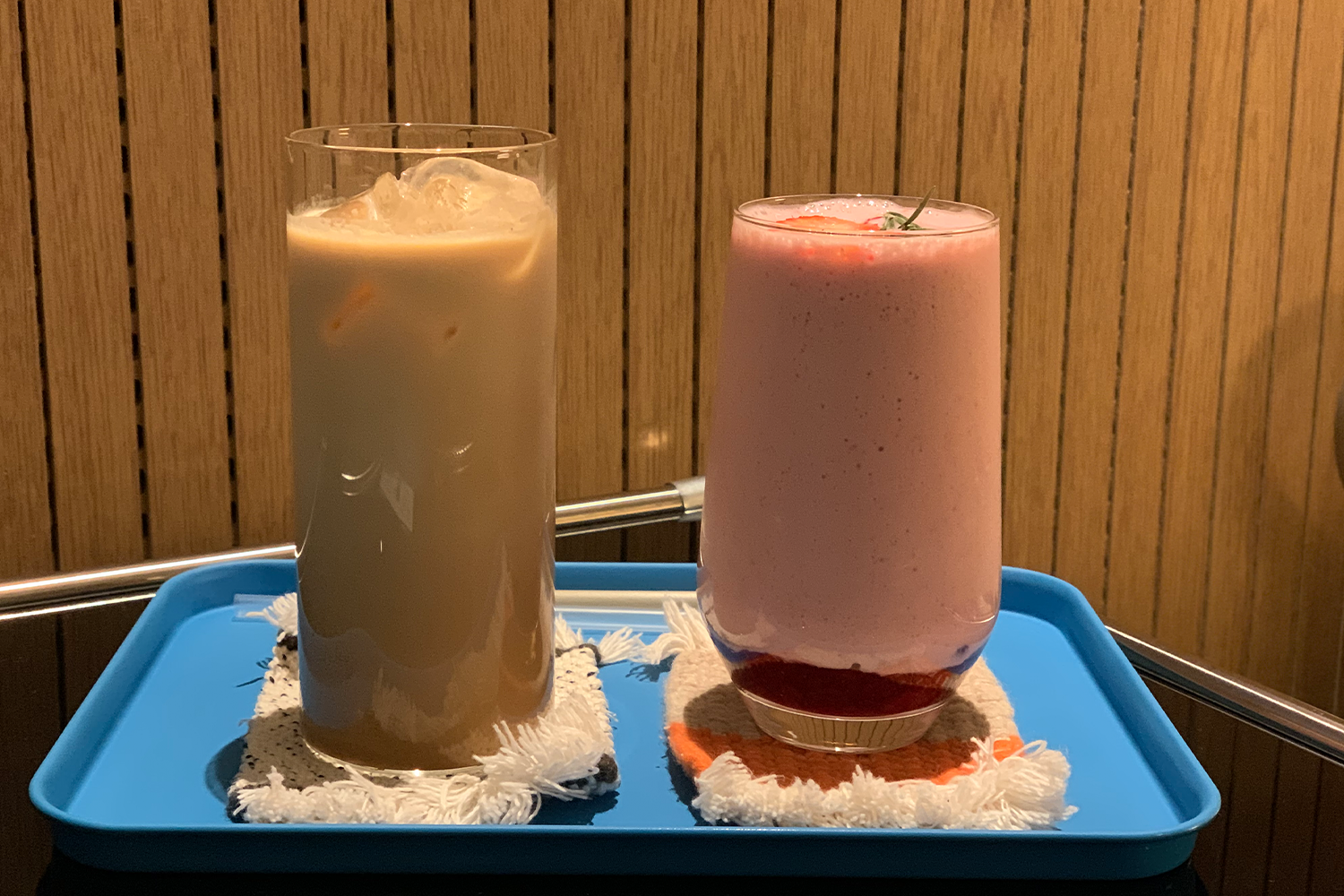 兩杯放於託盤上的飲品，分別是冰咖啡和草莓牛奶，位於釜山咖啡館內。