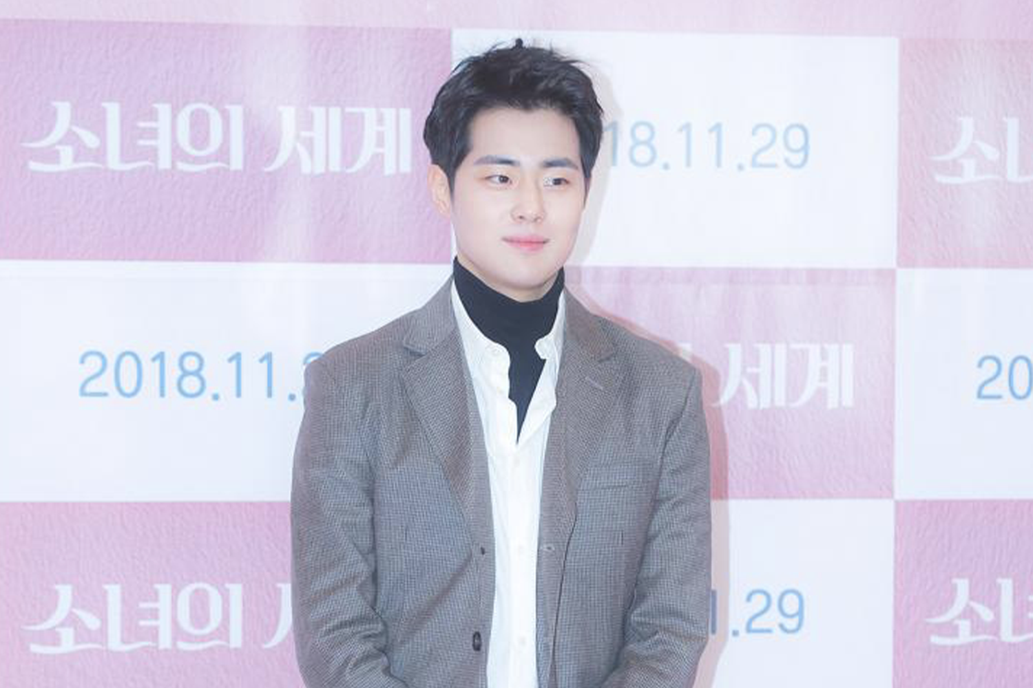 穿著灰色西裝與白襯衫的男性站在『少女的世界』海報前，顯示活動日期2018年11月29日。