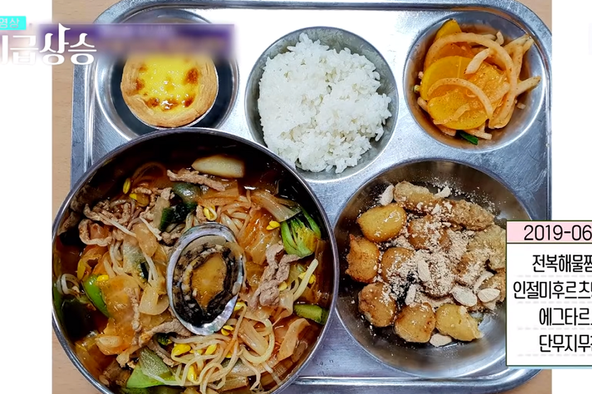 配有螃蟹和其他熱菜的韓國校園午餐，展示豐盛的餐盤設計。