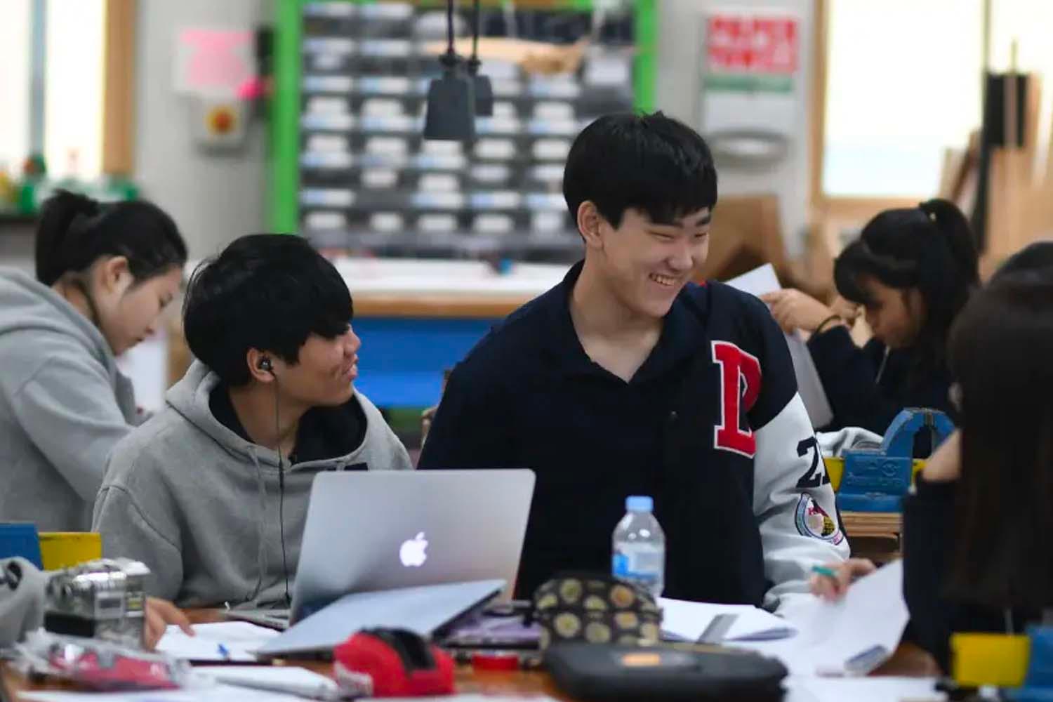 นักเรียนกำลังทำงานร่วมกันในแล็ปท็อป Apple ภายในห้องเรียนในเกาหลีใต้