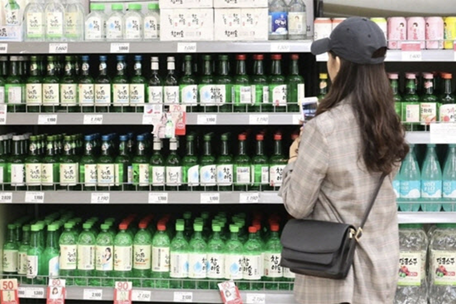 韓國超市內，女性顧客正在挑選架上陳列的多款韓國燒酒及其他酒精飲品。