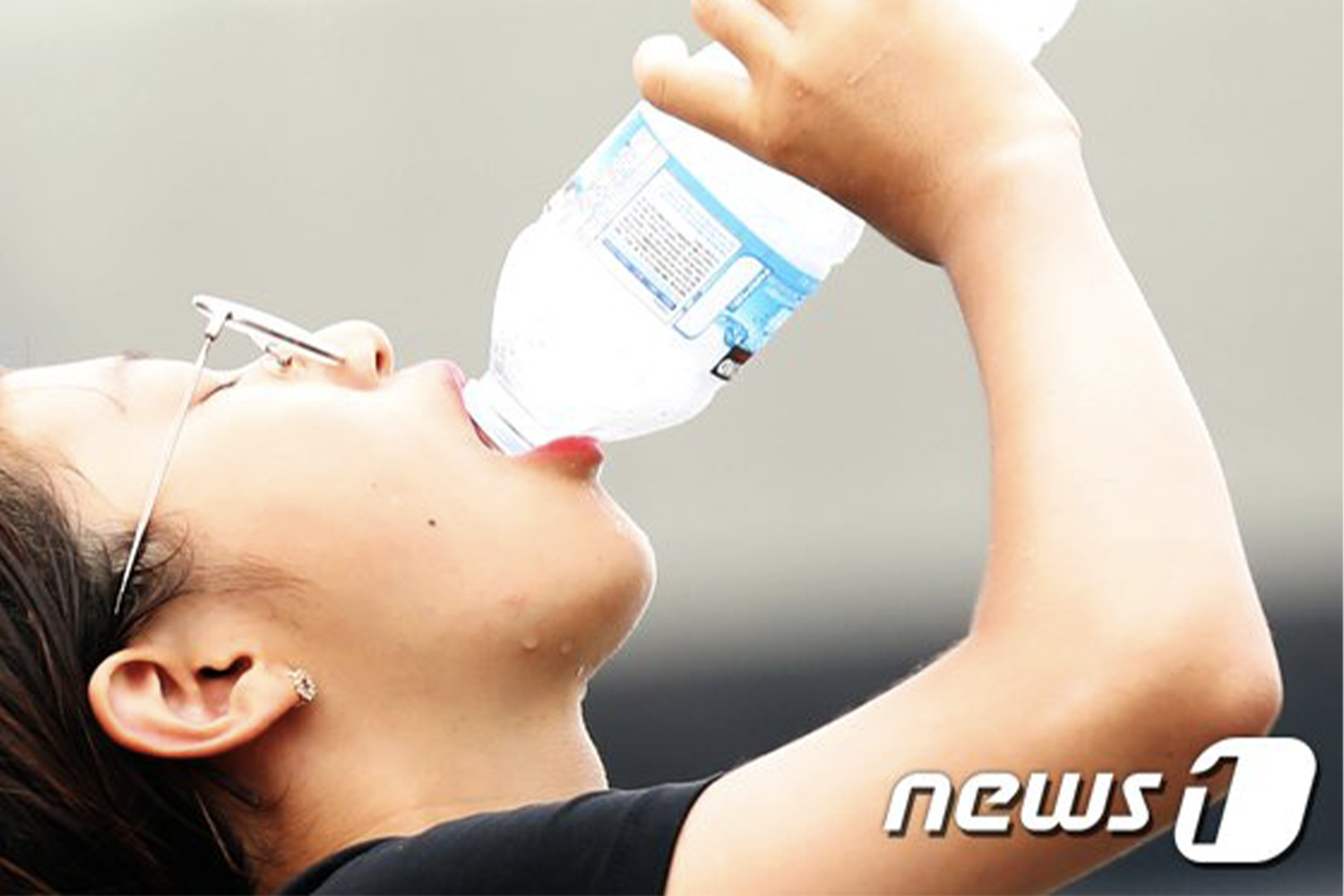 一位年輕女性正在享用一瓶冰凍水，此情景展示韓國人飲用冰水的日常習慣。