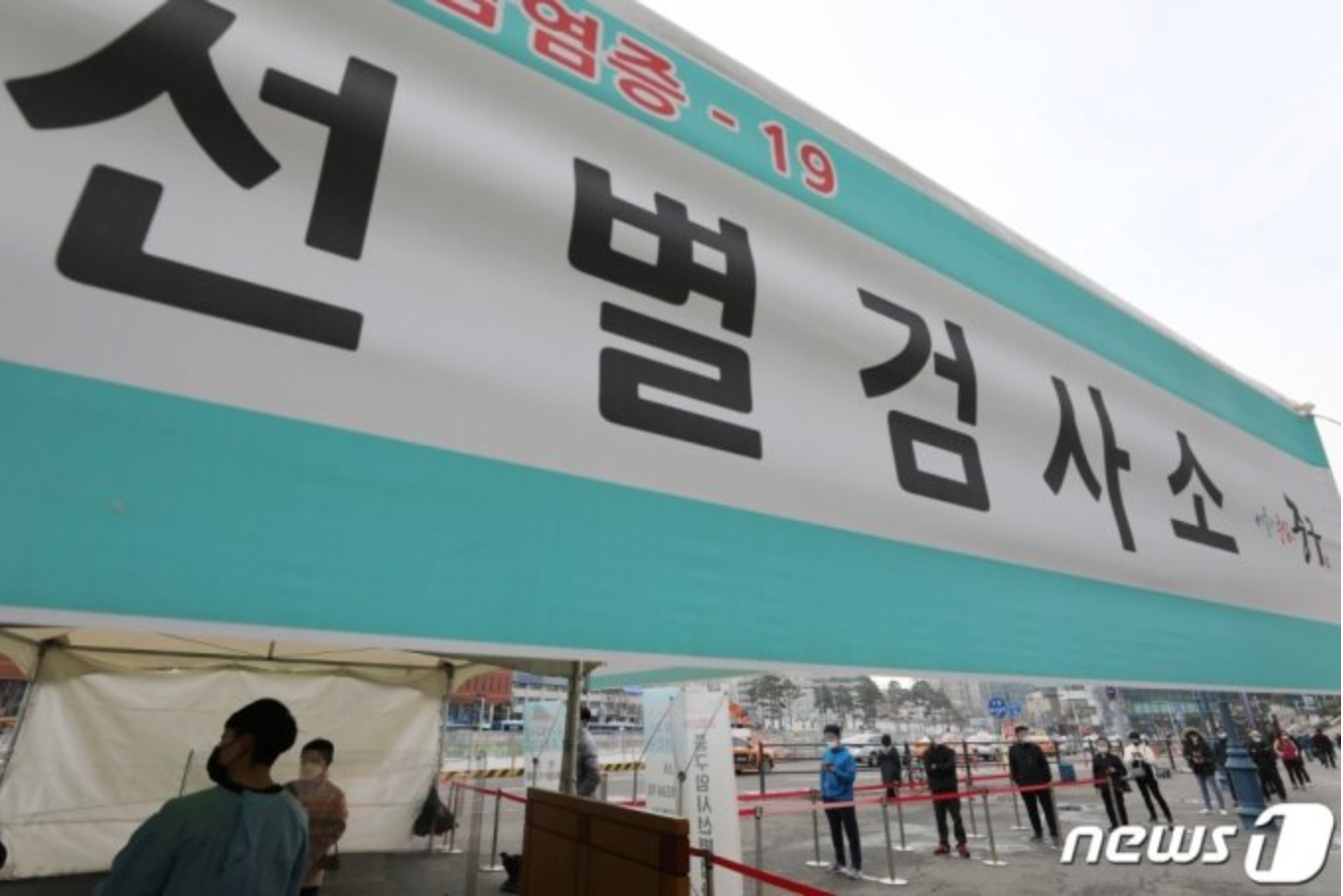 ป้ายศูนย์ตรวจคัดกรองโควิด 19 ในเกาหลีใต้ที่มีคนมาต่อคิวรอทำการตรวจเพื่อลดการแพร่ระบาดในพื้นที่