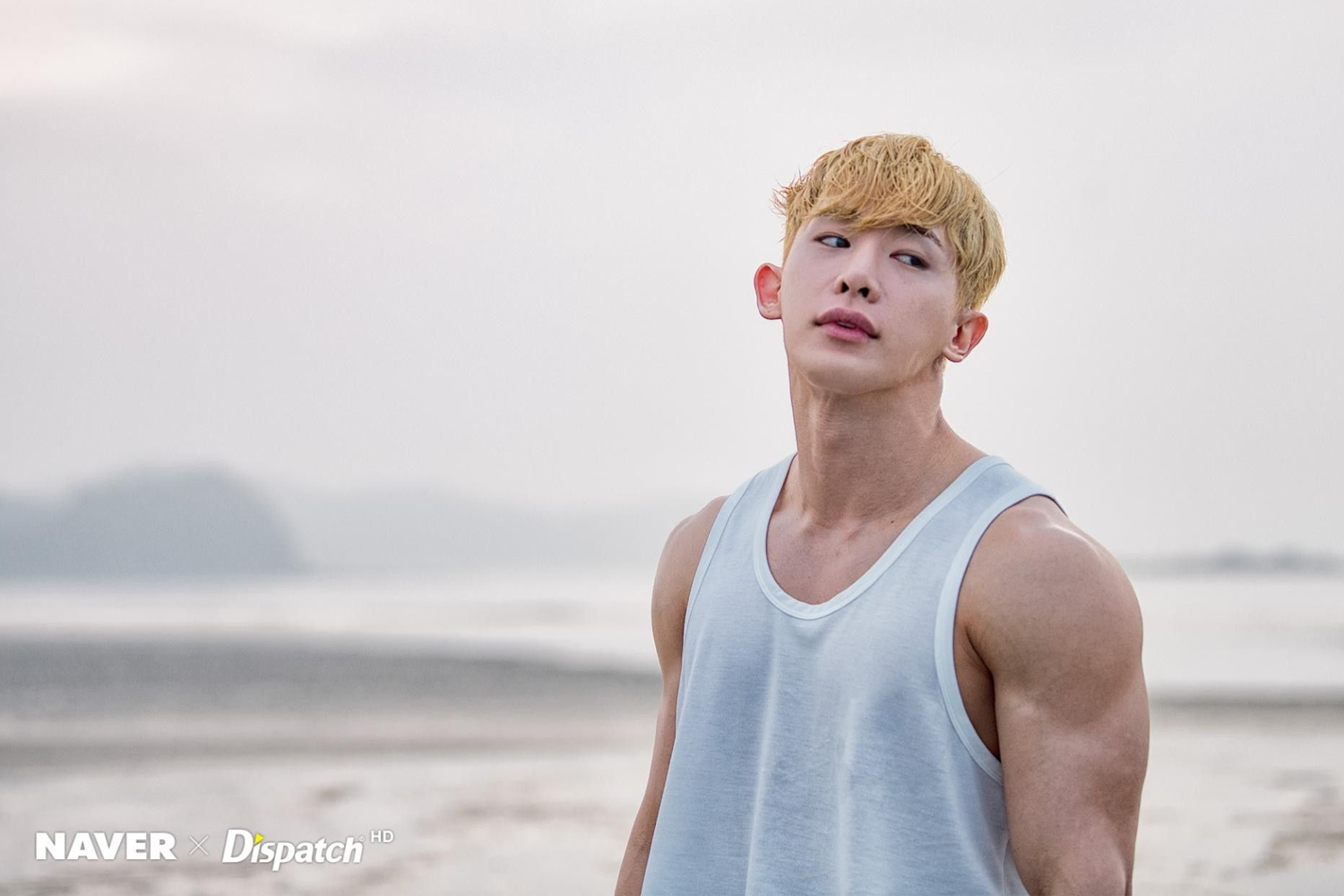 元虎站在海邊，穿著背心顯示出其強壯的身材。