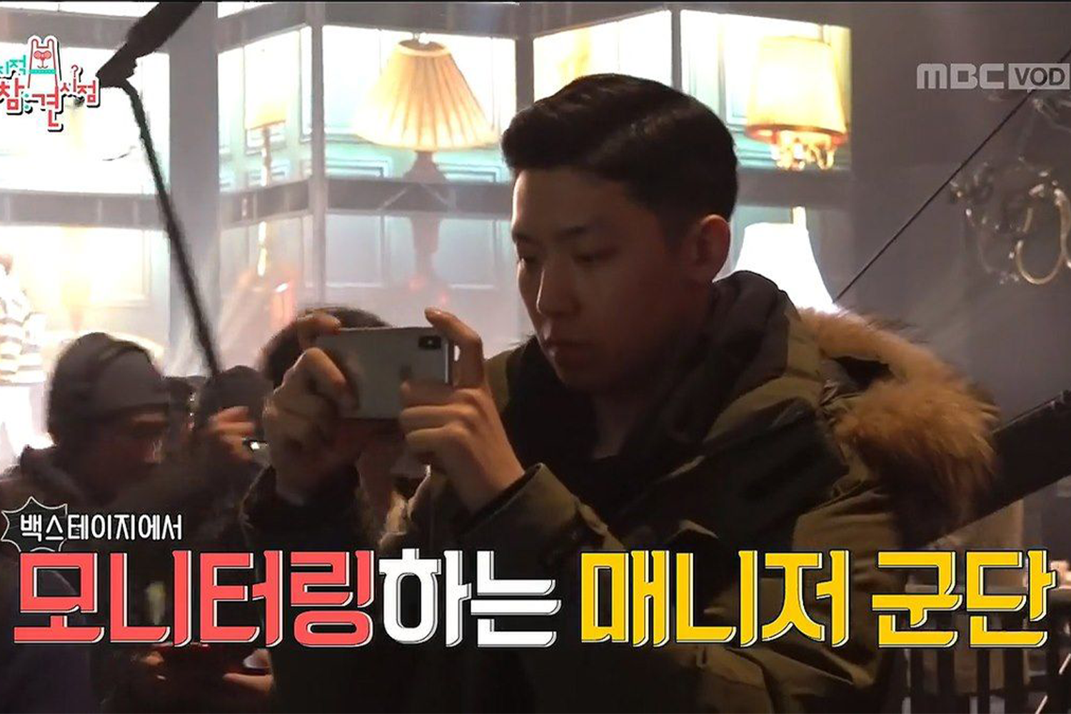 Un manager de SEVENTEEN surveillant une performance du groupe lors d'un spectacle