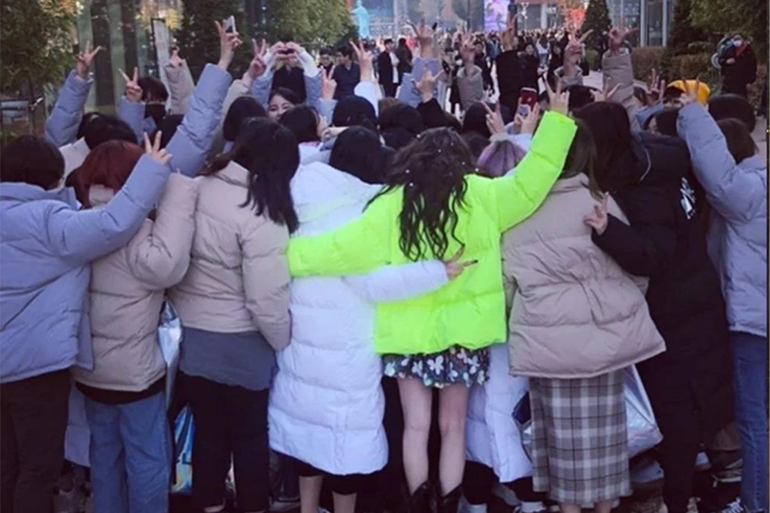 偶像粉絲與藝人合影，展示後方橫幅的認證照，以表達粉絲對偶像的支持和感謝。