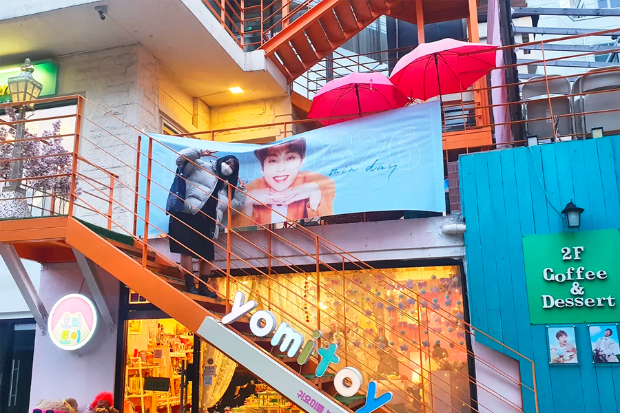 咖啡廳應援活動中的橫幅佈景，外部有粉絲拍攝照片
