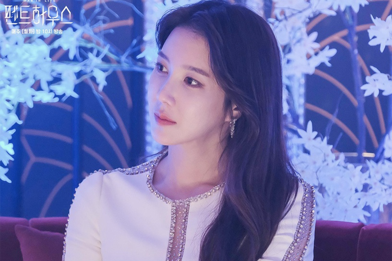 沈秀蓮坐在赫拉皇宮裏，穿著白色亮片裙，背景有奢華和藝術感的擺設。