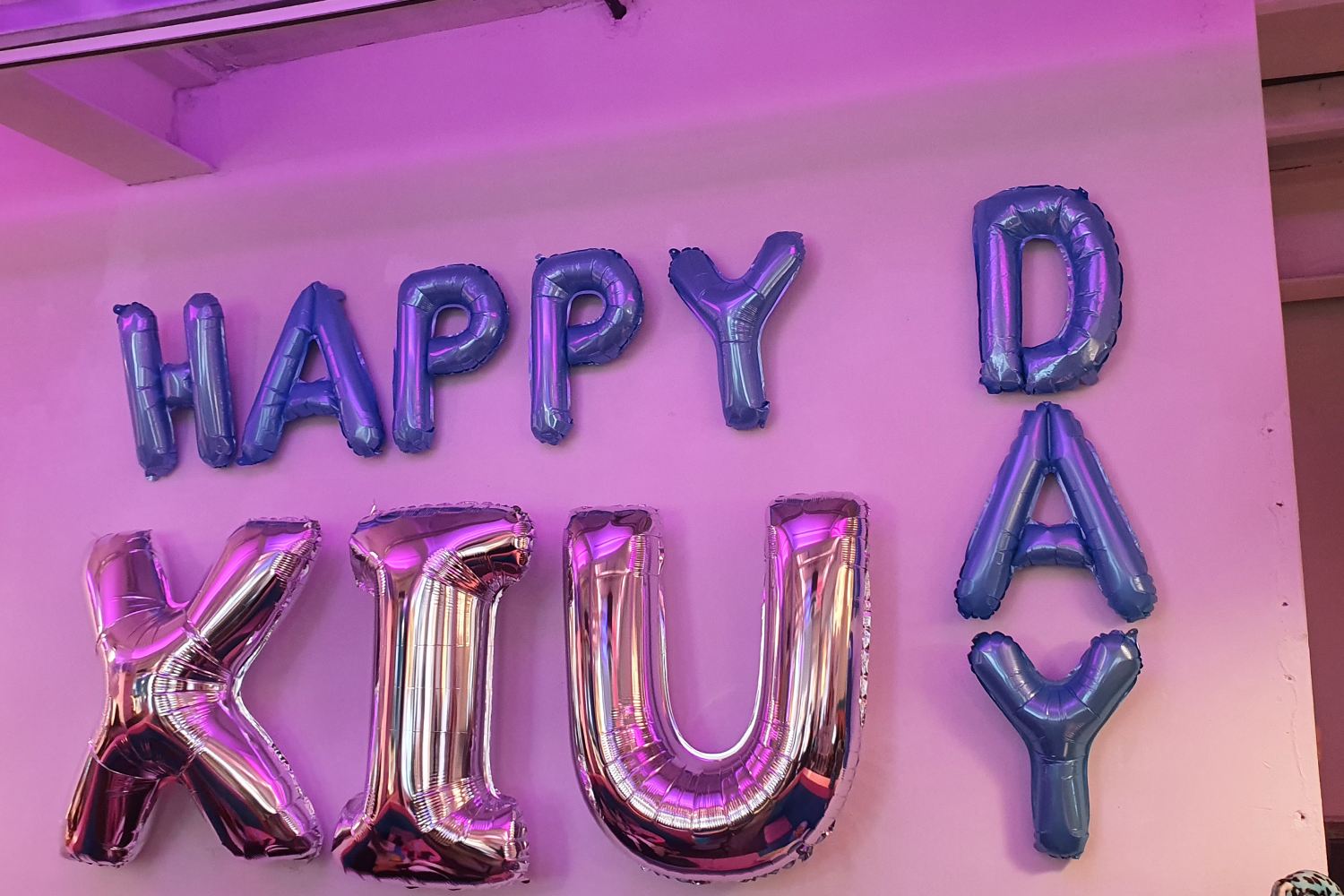 카페에서 제공되는 XIUMIN의 생일 기념 테이블 세팅. 생일 메시지가 장식된 공간과 함께 다양한 꽃들이 놓여 있다.