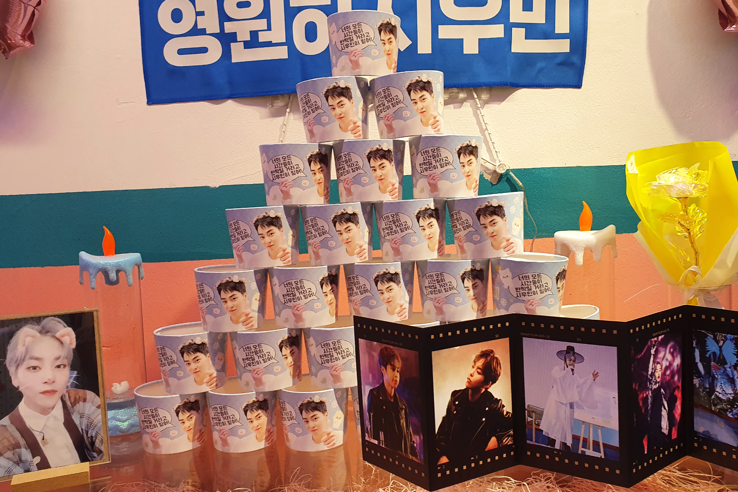 Happy Xiu Day 은색과 핑크색 풍선이 장식된 카페의 내부 모습.