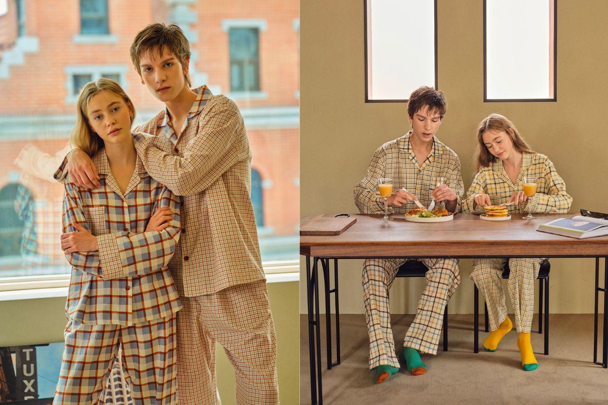 Một cặp đôi mặc đồ ngủ kẻ caro giản dị và ăn điểm tâm sáng trên bàn gỗ nhỏ, ánh sáng tự nhiên chiếu qua cửa sổ làm nổi bật không gian ấm cúng.