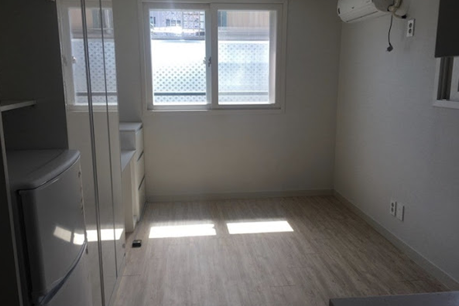 A set of wooden blocks resembling a house frame next to a calculator on a blue background, representing housing and rental costs in South Korea.