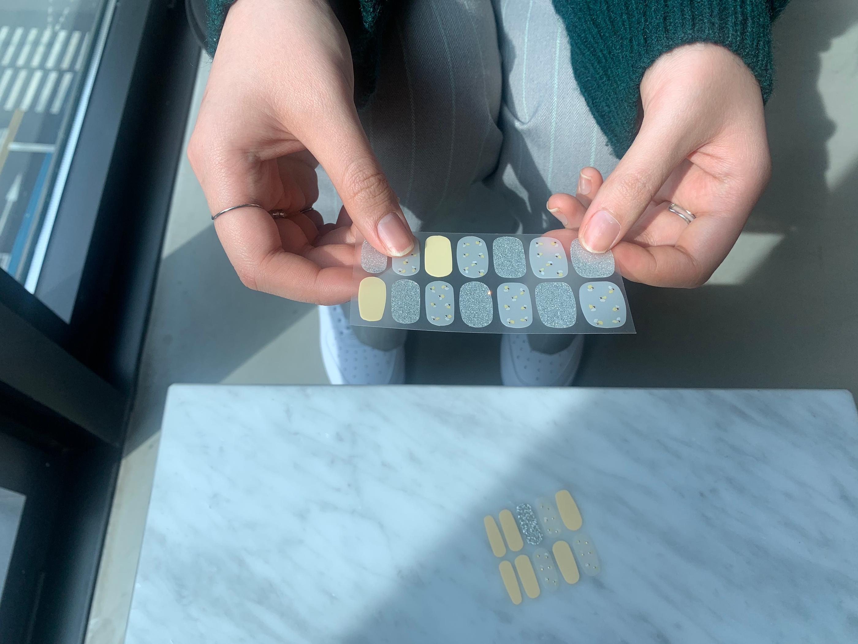 creatrip editor holding up one sheet of gelato factory nail sticker that are yellow and pattterend