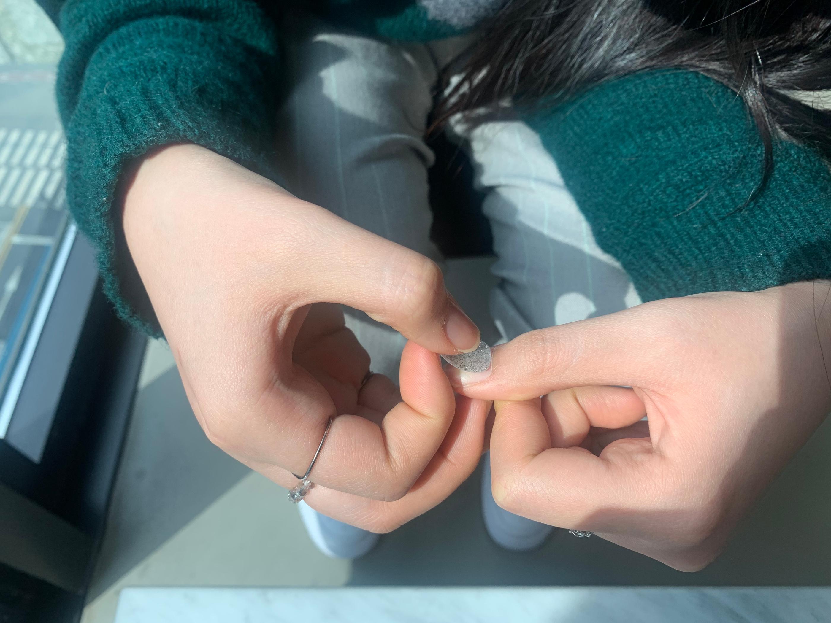 attaching silver glitter nail sticker to thumb nail