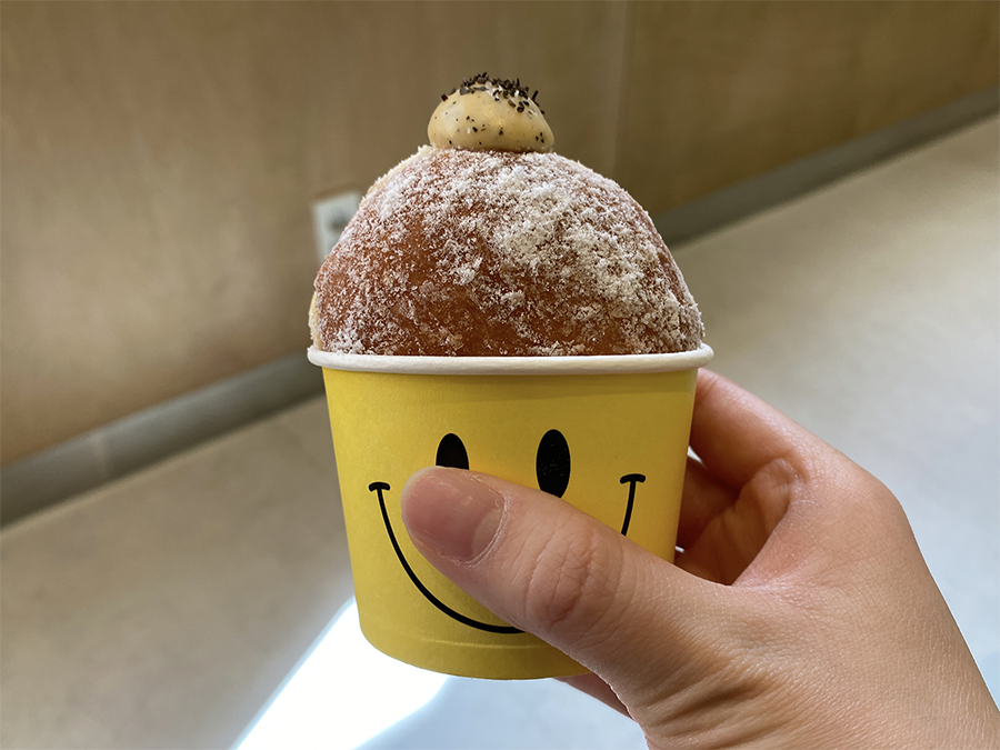 手拿著Cafe Knotted的一個大奶油甜甜圈，上面撒著糖粉。