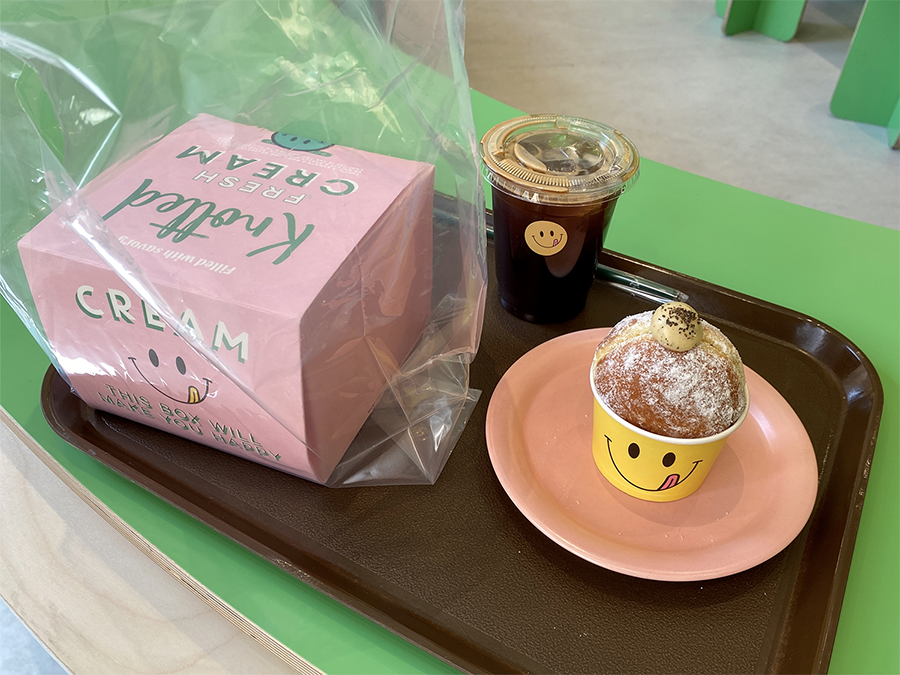 Cafe Knotted的餐盤，包括一杯冰咖啡和一個裝在黃色笑臉紙杯中的甜甜圈。