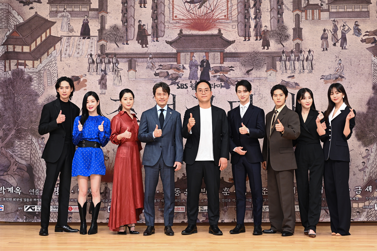 《朝鲜驱魔师》制作发布会现场演员合影，大背景为传统韩国宫殿画卷，演员们整齐排列，手举赞同手势。