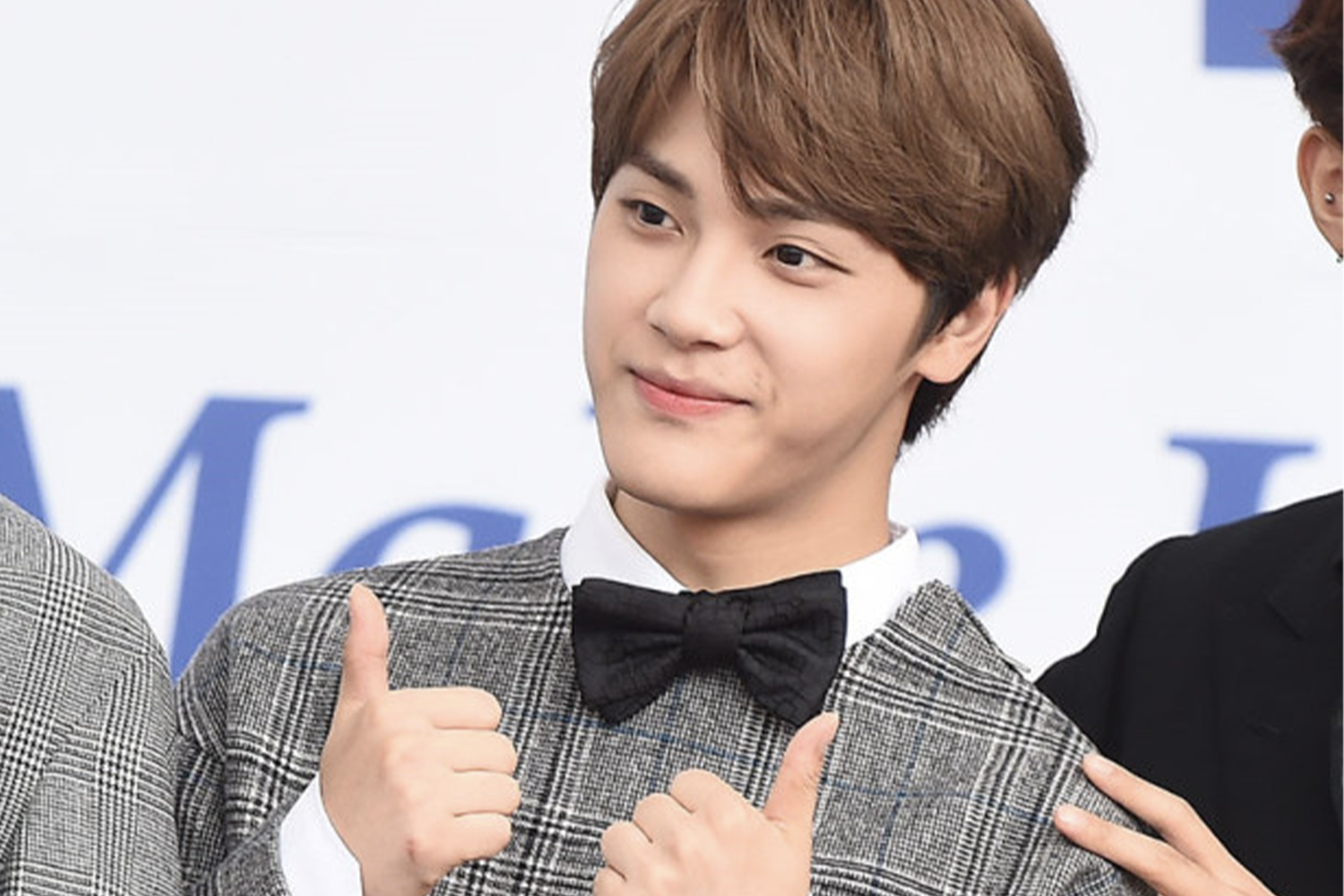 THE BOYZ成員周鶴年穿著西裝配領結，展示雙手大拇指姿勢