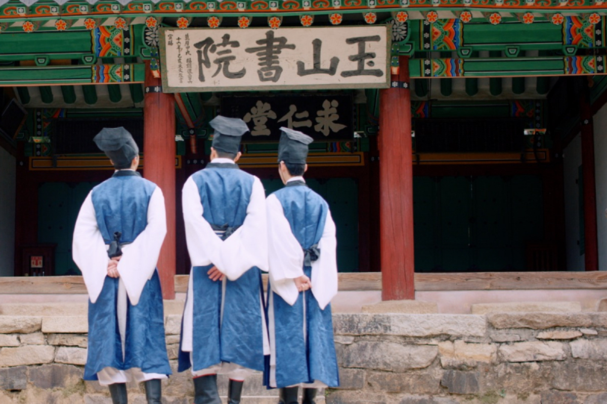 一群身着传统服饰的书生，在考试接待厅前康庄的环境中，显示出典雅的风格。