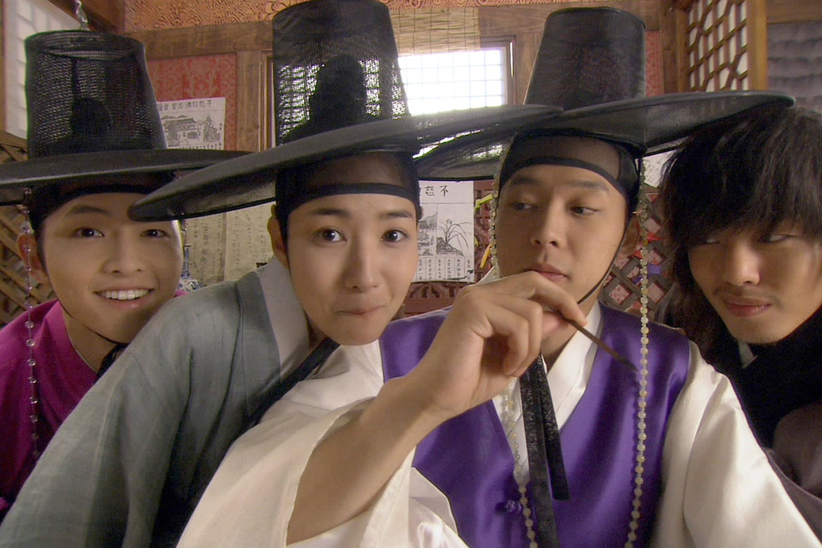 儒生们站在古代建筑前，背对观众，身着整齐的深蓝色韩服，背景是一座传统的书院。