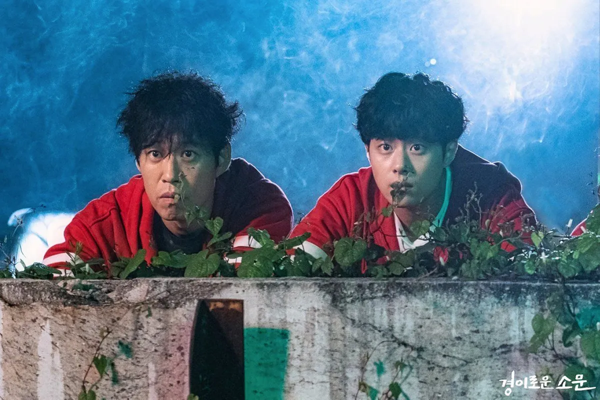 韩剧《驱魔面馆》剧照，夜间两位角色身穿红色运动服在屋顶观察，气氛紧张