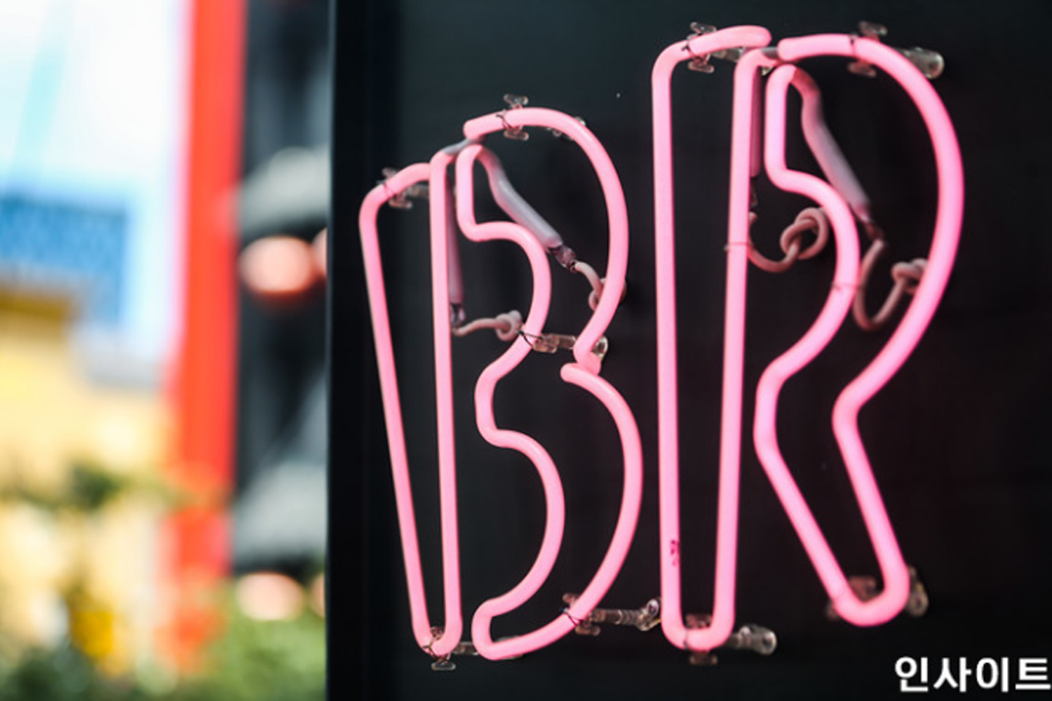 花都分為韓國BR品牌特寫霓虹燈的照片，這個BR標誌以鮮豔的粉紅色呈現，背景模糊，為即將停售薄荷朱古力口味的概念影響帶來戲劇化背景。