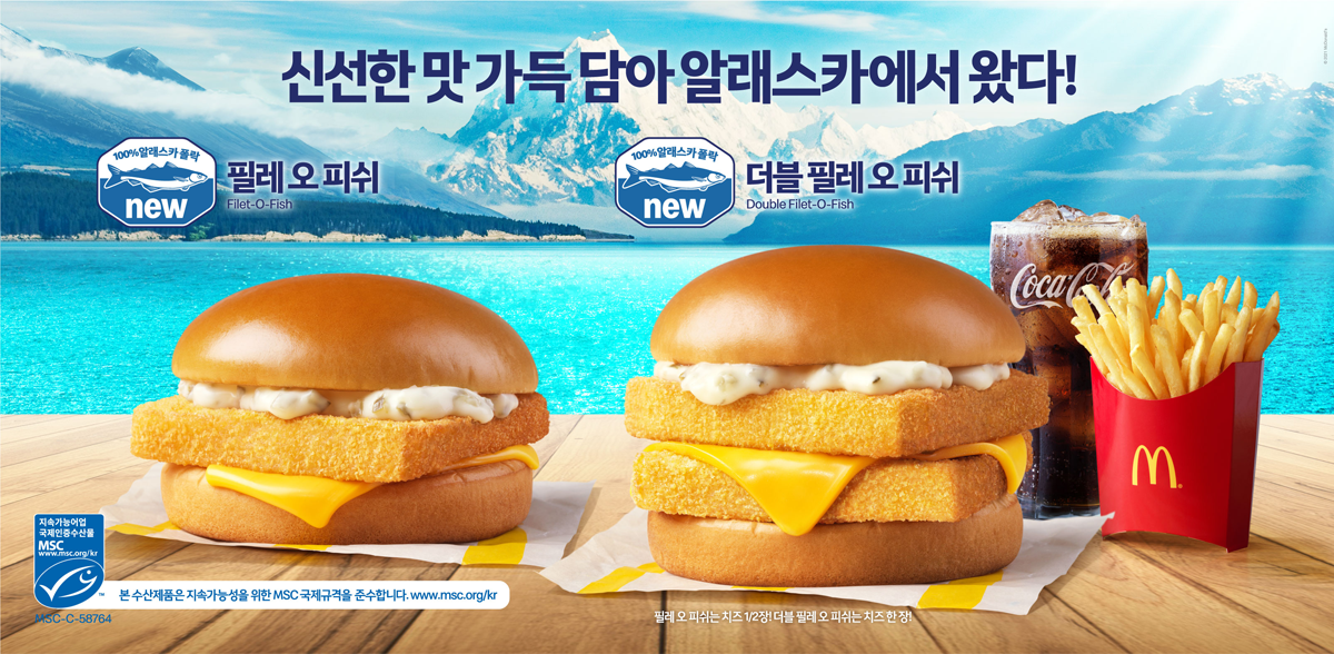 麦当劳韩国的麦香鱼堡广告图片,展示汉堡的成分,包括炸鱼饼,奶酪和面包。背景中是碧蓝的湖和覆盖积雪的山峰。