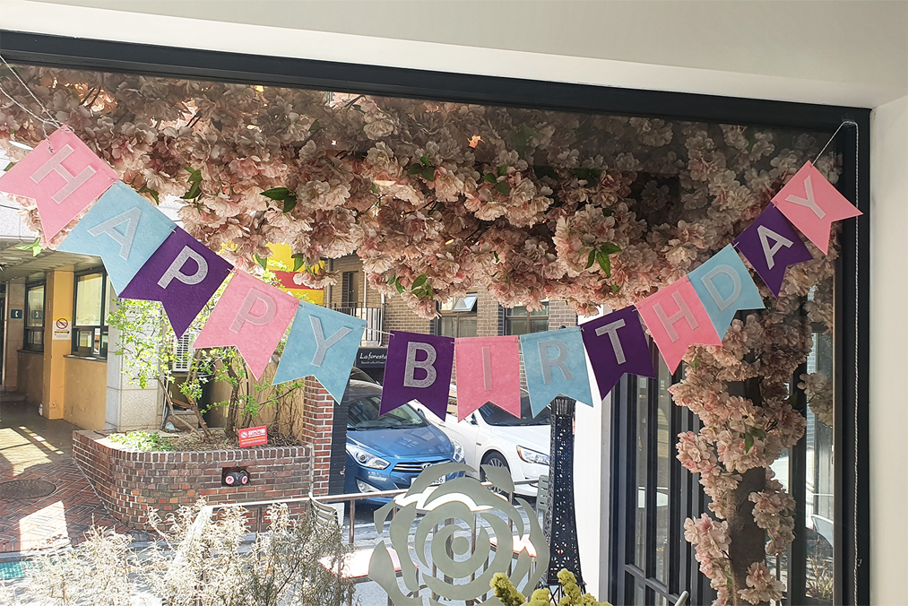 窗户上掛著色彩繽紛的生日祝賀彩旗，充滿了歡樂和節慶的氣氛。
