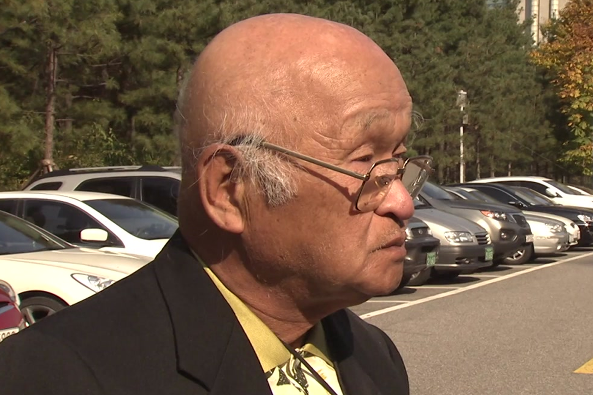 鄭元燮在戶外接受新聞採訪的畫面，背景是停車場。