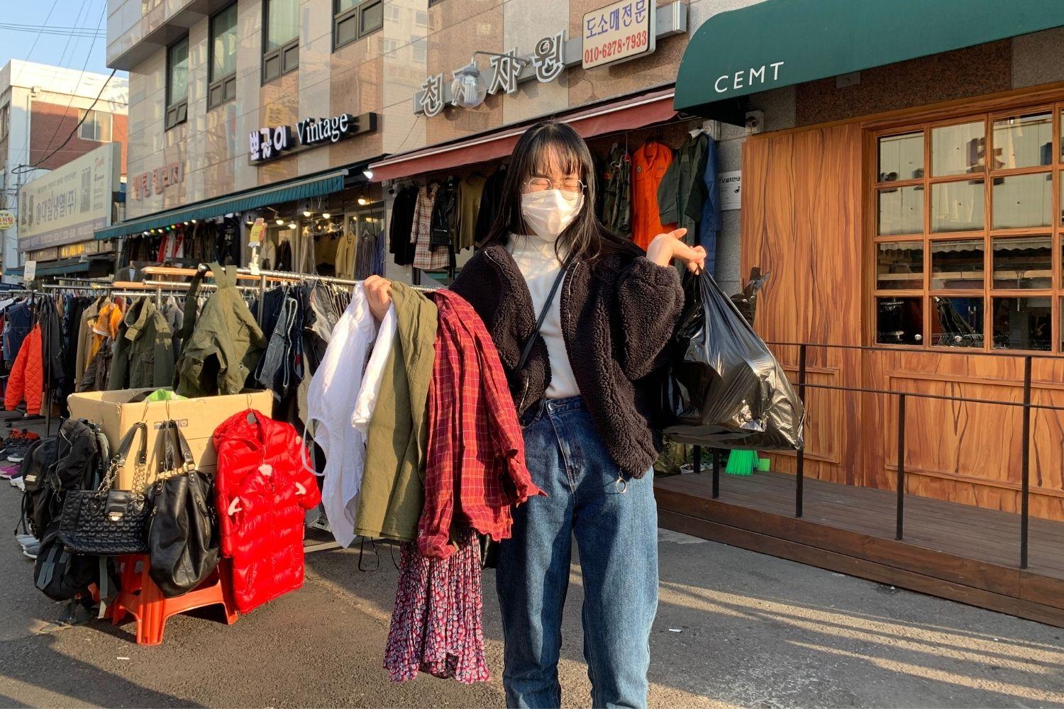 girl holding up clothes at dongmyo flea market