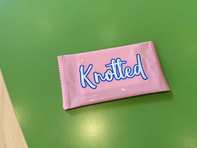 Милые салфетки в розовой упаковке с логотипом Knotted, выставленные на столе в кафе Knotted, Сеул.