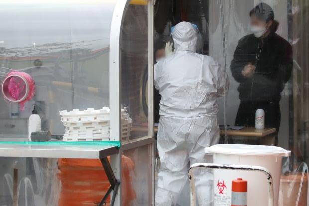 防護服を着た医療スタッフが診療所で新型コロナウイルス感染症の診断テストを行っている様子