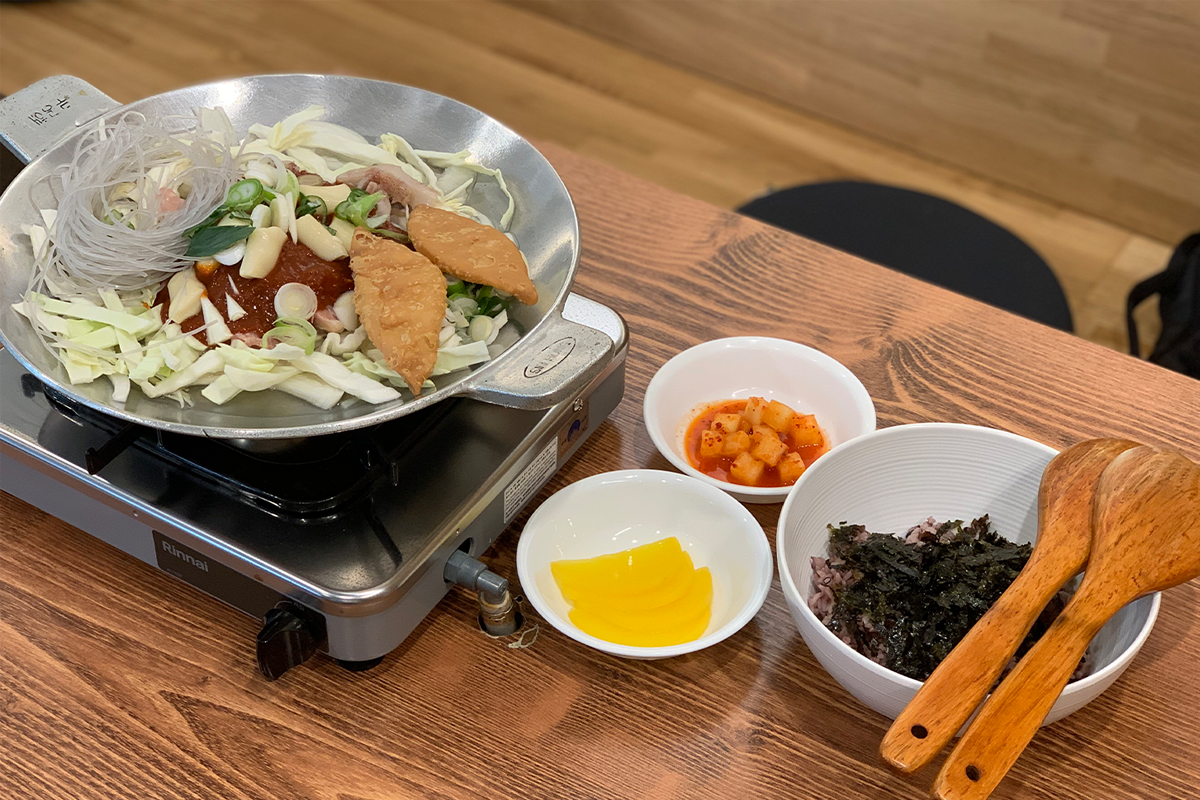 梨大火飯準備完成，旁邊搭配泡菜與黃色醃蘿蔔，韓式經典佐餐小菜，為美味加分。