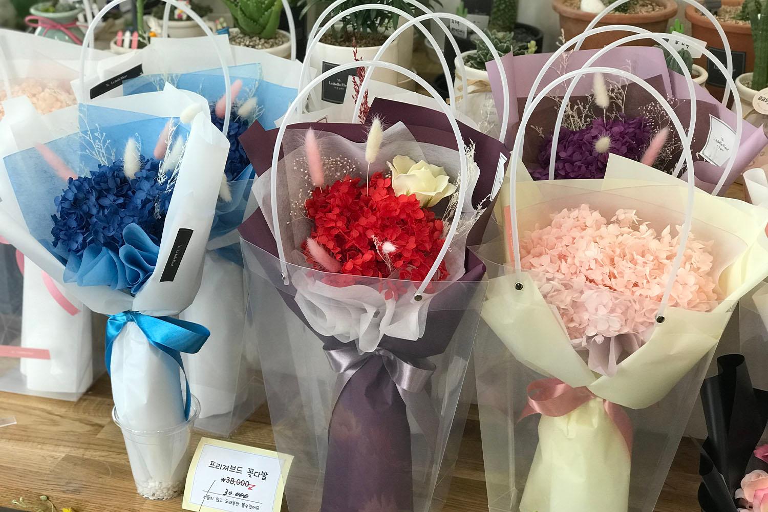 ช่อดอกไม้แห้งหลากสีในกระดาษบรรจุที่ผูกด้วยริบบิ้นอย่างสวยงามในร้านดอกไม้ที่ชินชน