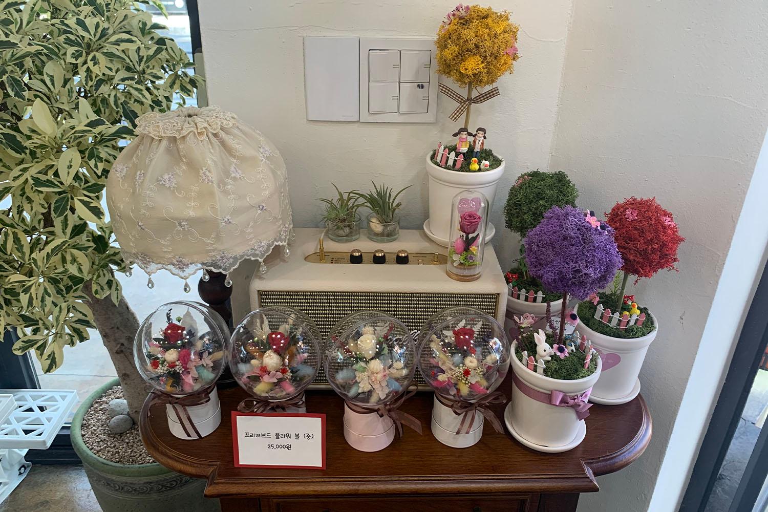 ลูกแก้วที่ใส่ดอกไม้ประดับในกระถางเล็ก ๆ บนโต๊ะในร้านดอกไม้ที่ชินชน