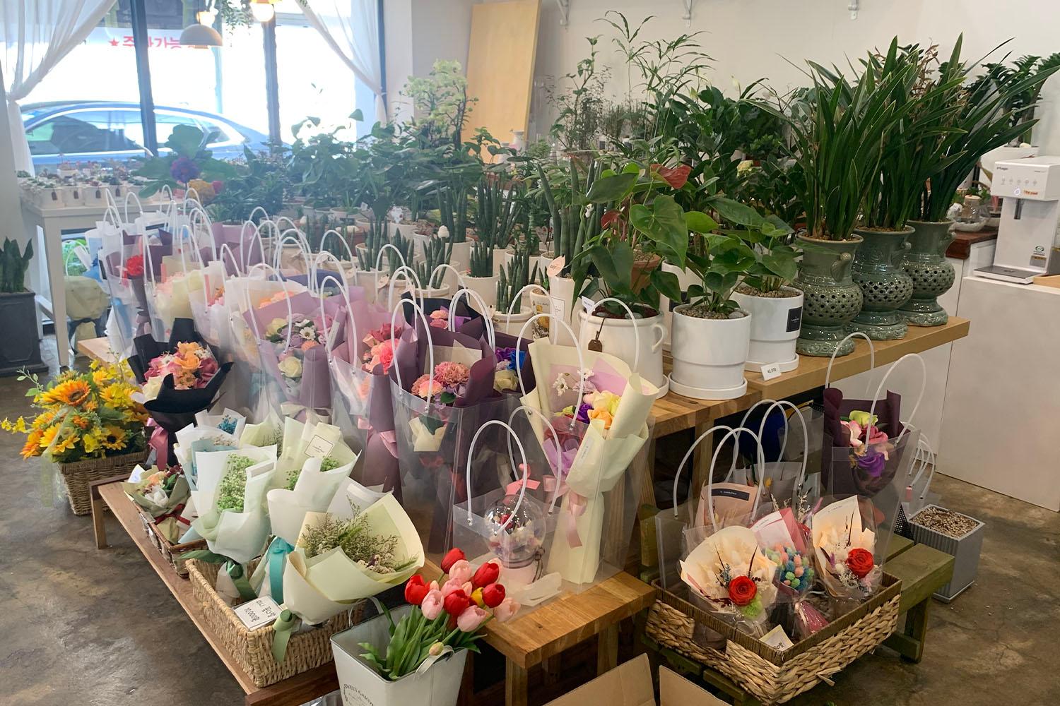 ดอกไม้สีสันสดใสและไม้กระถางที่จัดเรียงอย่างประณีตบนโต๊ะในร้านดอกไม้ที่ชินชน ประเทศเกาหลีใต้