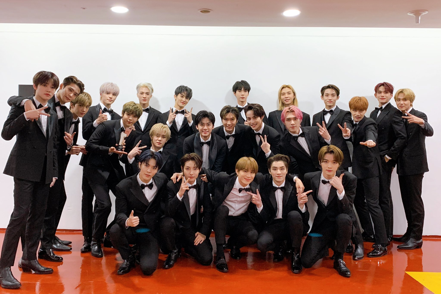 NCT舞台正式演出前的後台合影，成員們穿着正裝，表現出一種深厚的兄弟友情。