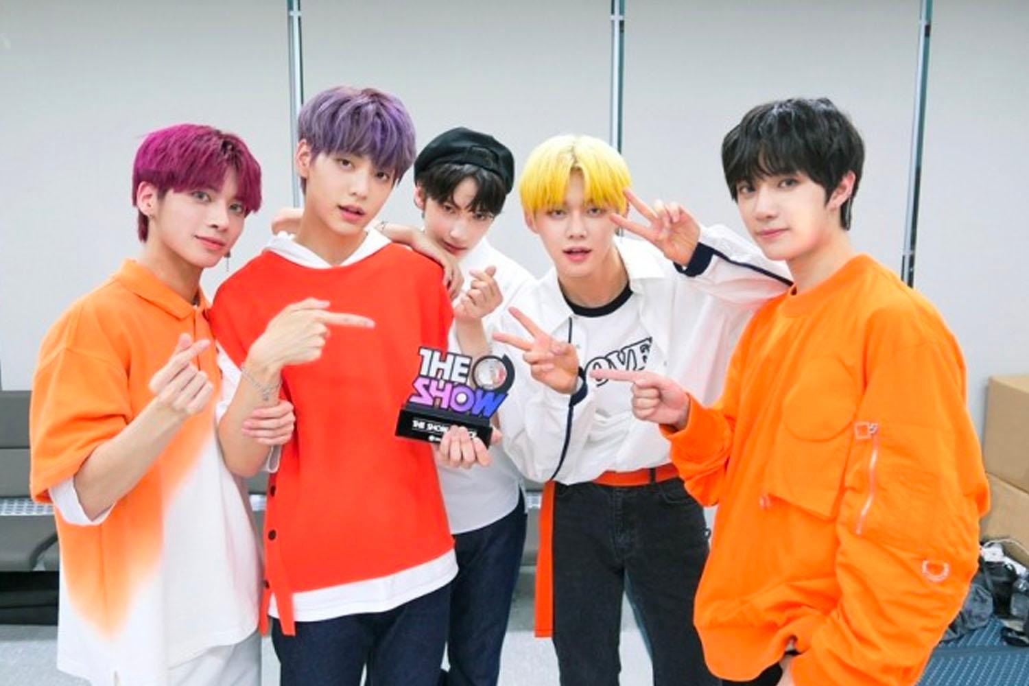 TXT成員的舞台後台合影，所有人都身着色彩鮮豔的服裝，傳遞出他們對音樂的熱情。