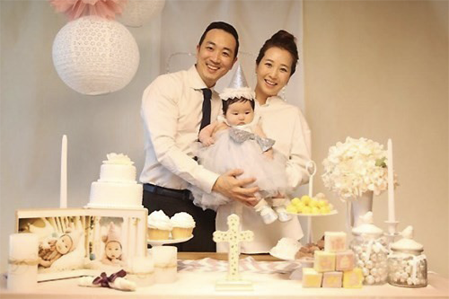 慶祝嬰兒100日百日宴的一家三口,在佈置華麗的派對背景中合影