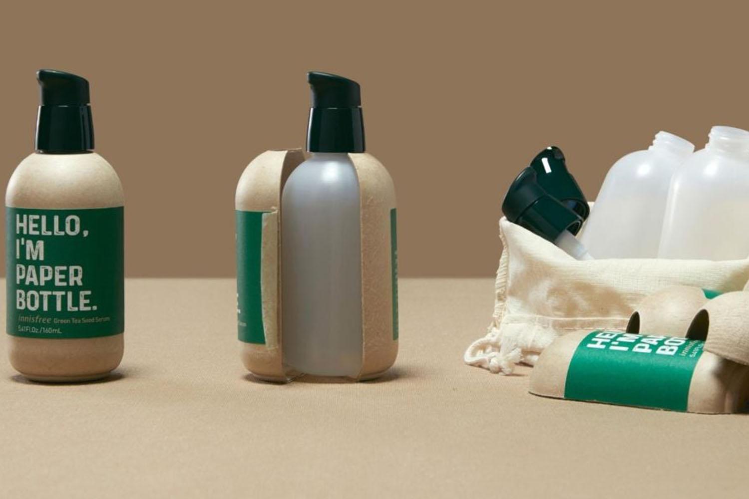 รูปขวด Innisfree Green Tea Seed Serum พร้อมกับการเปิดเผยภายในที่เป็นขวดพลาสติกเคลือบด้วยกระดาษ มีข้อความว่า 'Hello, I'm Paper Bottle'