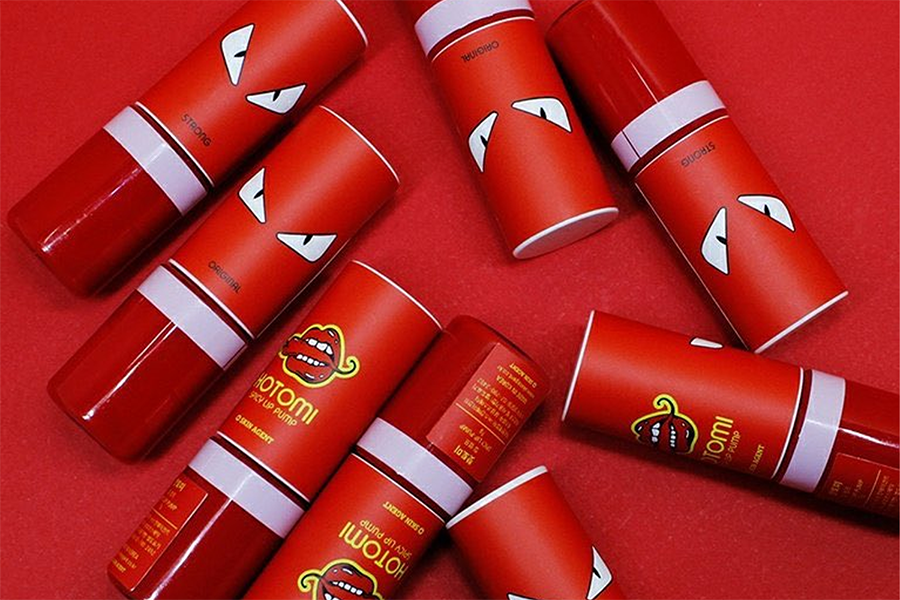 Hot Tommy辛辣唇彩產品擺設在紅色背景上，展示其獨特辛辣唇彩的外觀設計。