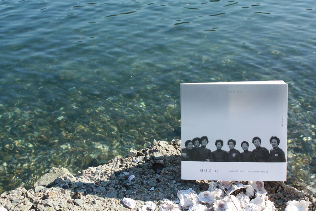 Buku Haenyeo dan saya di atas batu dekat laut