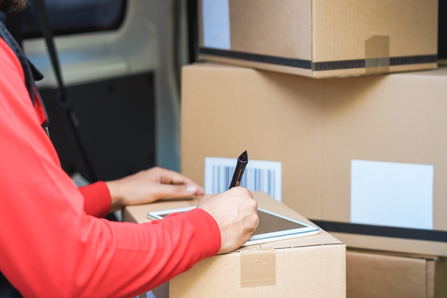 delivery man making notes on tablet on package