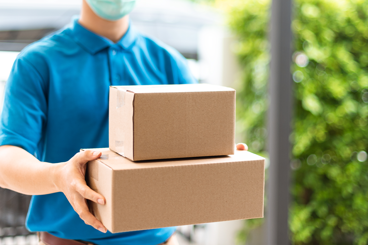 Repartidor con mascarilla entregando cajas, resaltando la entrega rápida y segura durante la pandemia.