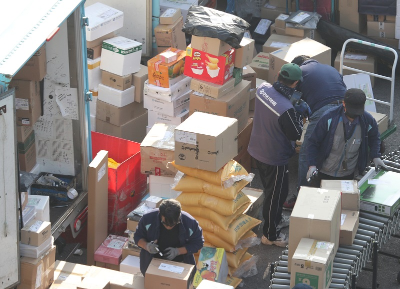 Repartidores trabajando con cajas y paquetes, mostrando el proceso de entrega y la carga de trabajo en el sector logístico.