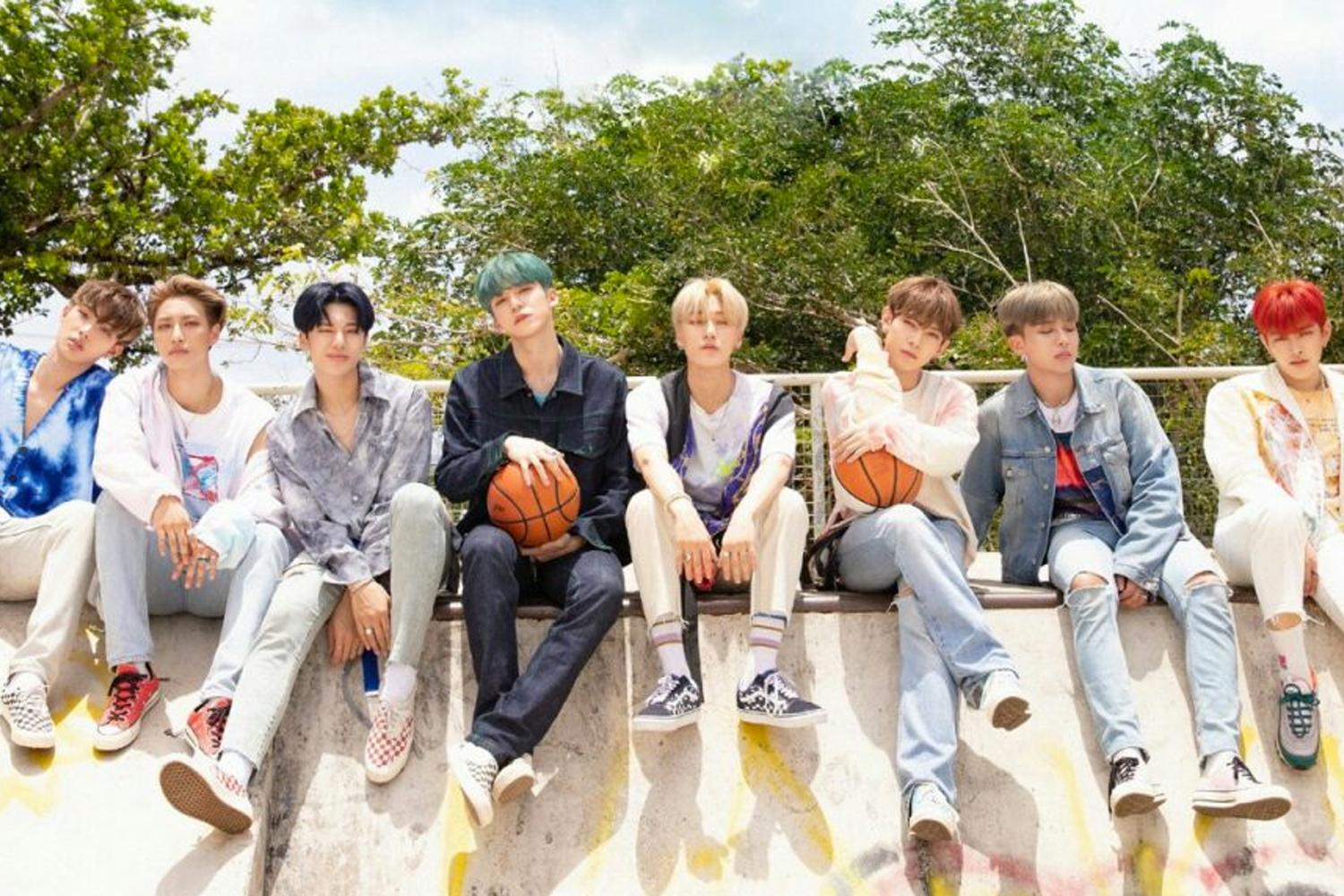 สมาชิก ATEEZ กำลังพักผ่อนอย่างสนุกสนานที่สนามกีฬาในเทศกาลฤดูร้อนในภาพโปรโมทเพลง Wave