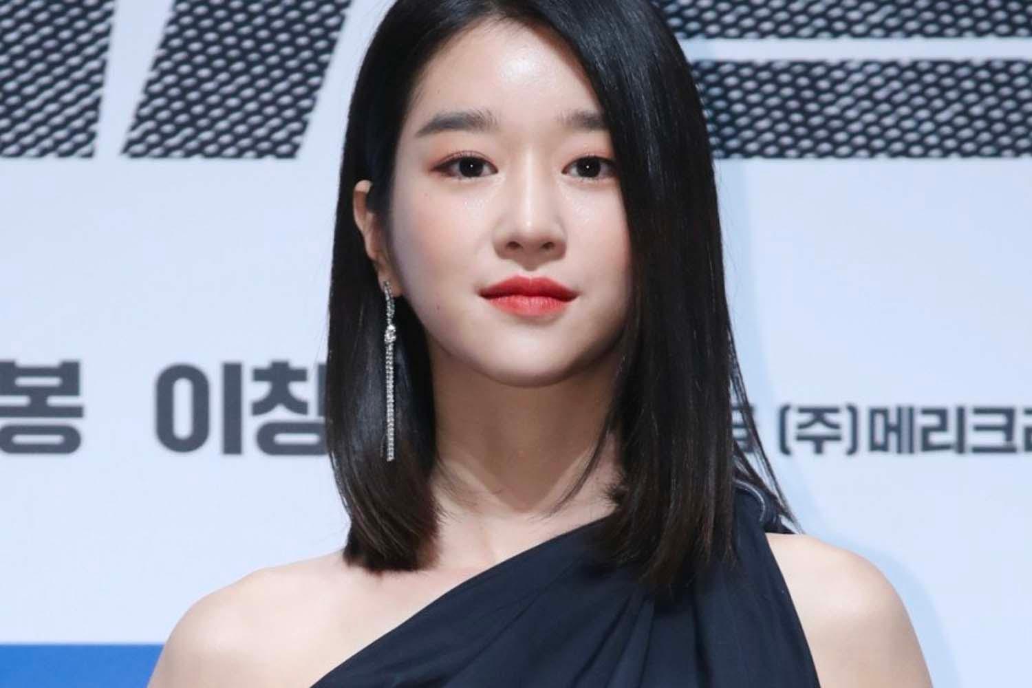 หญิงสาวในชุดสีดำที่มีการออกแบบที่หรูหราตัดกับพื้นหลังสีขาว