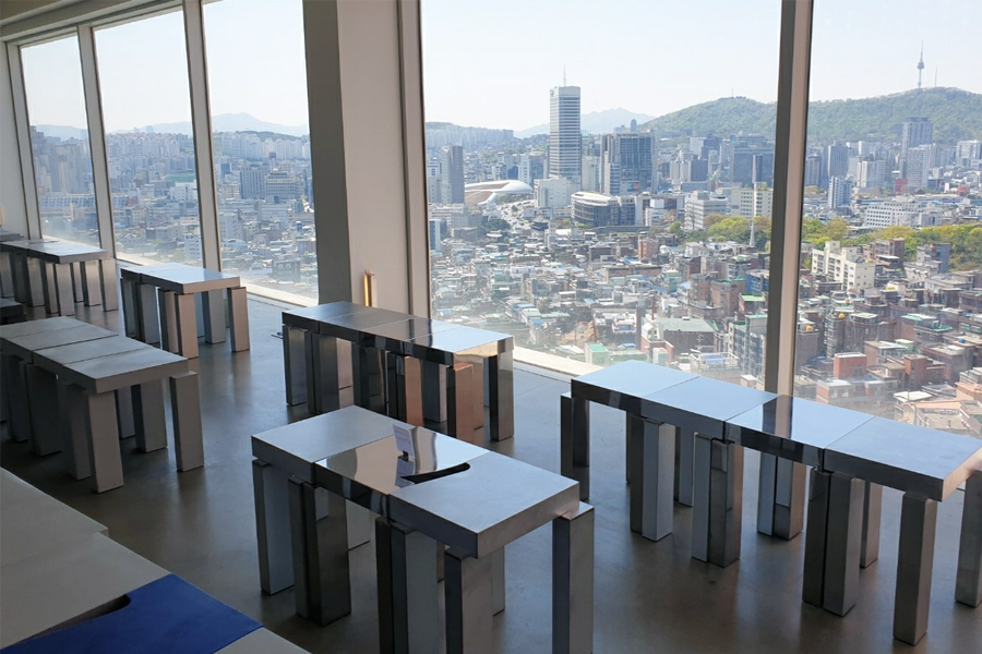 T(ER)T(RE)咖啡厅室内景观，桌椅布置简约而整洁，大窗户外是广阔的城市风景，突出咖啡厅的休闲和舒适氛围。