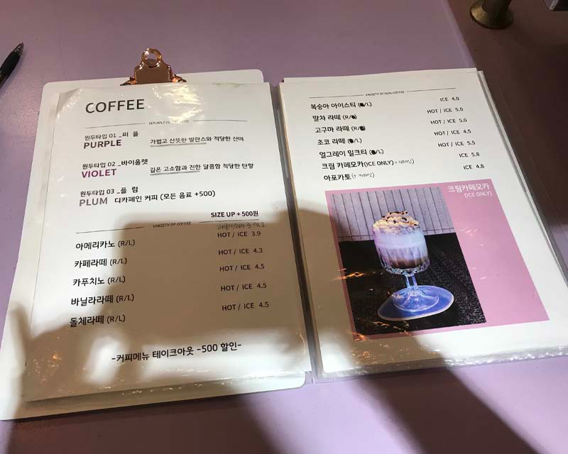 Menú de bebidas del Cafe Be Purple en Seúl, destacando opciones como Purple y Violet café en un entorno pastel.